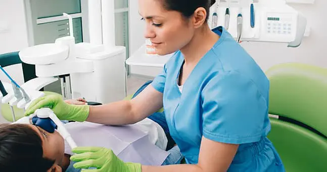 Dental assistant working with child in dental office.