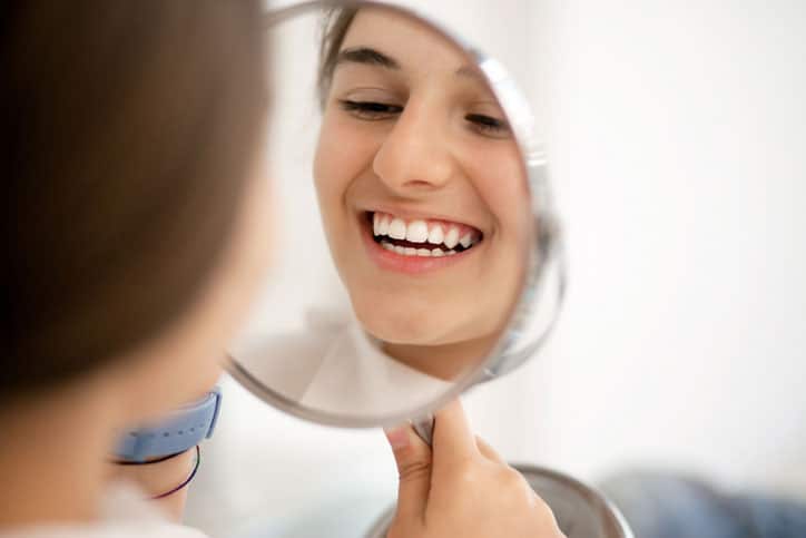 Cute teenage girl looking at her teeth in the mirror